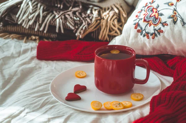 Czerwony kubek herbaty z kumkwat i dwa serca ciasteczka na białym łóżku. Cozy Home. Koncepcja Walentynki — Zdjęcie stockowe
