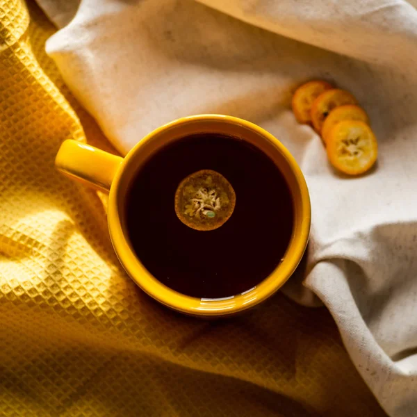 Tasse mit Tee Kumquat auf gelbem Hintergrund — Stockfoto