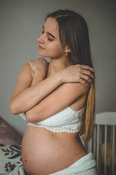 Attraktive Schwangere sitzt im Bett und hält ihren Bauch. Die letzten Monate der Schwangerschaft. — Stockfoto