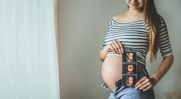 Femme enceinte tenant une image échographique . — Photo