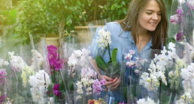 Perakende mağazasında renkli çiçekaçan orkide kokulu güzel kadın müşteri. 