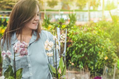 Perakende mağazasında renkli çiçekaçan orkide kokulu güzel kadın müşteri. 