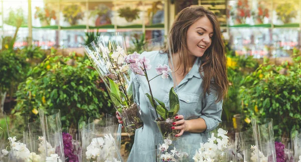 Красива жінка-клієнт пахне барвистими квітучими орхідеями в роздрібному магазині . — стокове фото