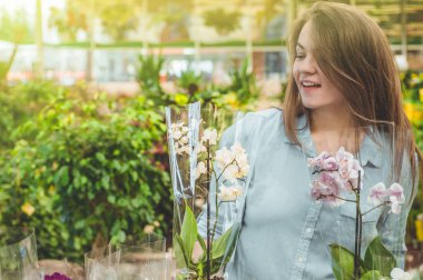 Perakende mağazasında renkli çiçekaçan orkide kokulu güzel kadın müşteri. 