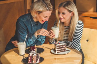 Bir kafede oturan iki mutlu kadın bir kokteyl içmek, birbirlerine komik hikayeler, iyi bir ruh halinde olmak mutlu bir şekilde gülerek söyle