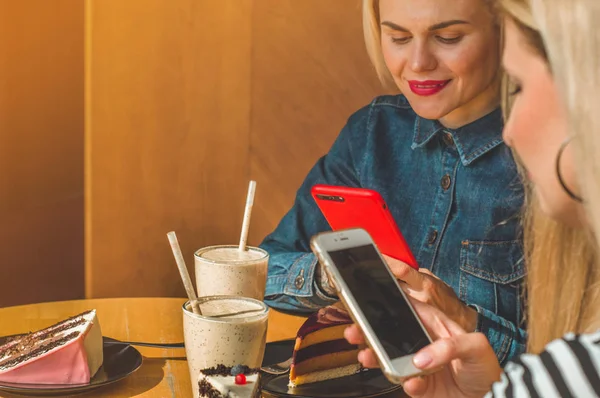 Dua wanita bahagia duduk di kafe dan mengambil foto selfie di telepon, minum koktail, saling menceritakan kisah lucu — Stok Foto