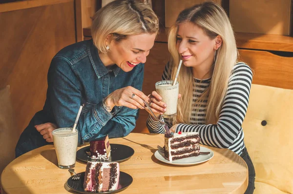 Bir kafede oturan iki mutlu kadın bir kokteyl içmek, birbirlerine komik hikayeler, iyi bir ruh halinde olmak mutlu bir şekilde gülerek söyle