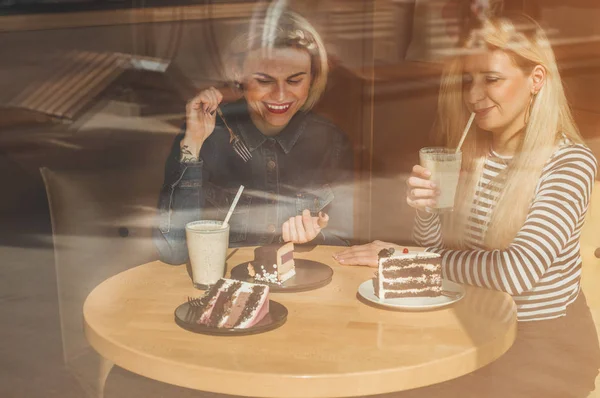 Dua wanita bahagia duduk di kafe, minum koktail, saling menceritakan kisah lucu, sedang dalam suasana hati yang baik, tertawa bahagia — Stok Foto