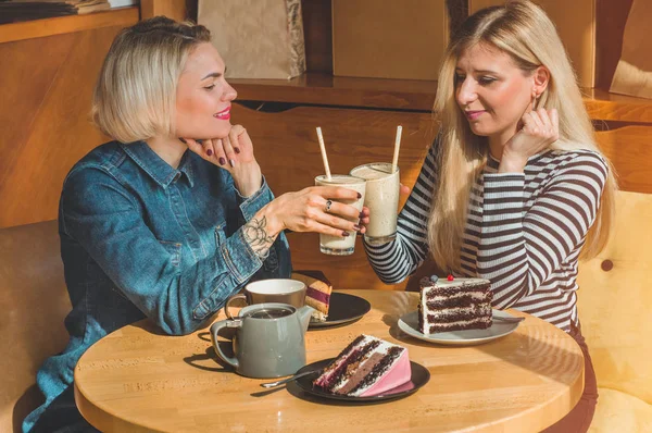 Bir kafede oturan iki mutlu kadın bir kokteyl içmek, birbirlerine komik hikayeler, iyi bir ruh halinde olmak mutlu bir şekilde gülerek söyle