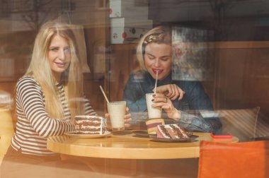 Bir kafede oturan iki mutlu kadın bir kokteyl içmek, birbirlerine komik hikayeler, iyi bir ruh halinde olmak mutlu bir şekilde gülerek söyle