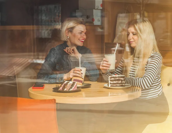 Dua wanita bahagia duduk di kafe, minum koktail, saling menceritakan kisah lucu, sedang dalam suasana hati yang baik, tertawa bahagia — Stok Foto