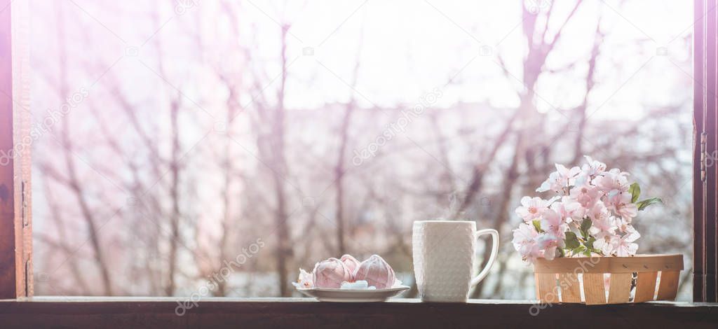 Cozy spring still life: cup of hot tea with spring bouquet of flowers on vintage windowsill with a pink marshmallow