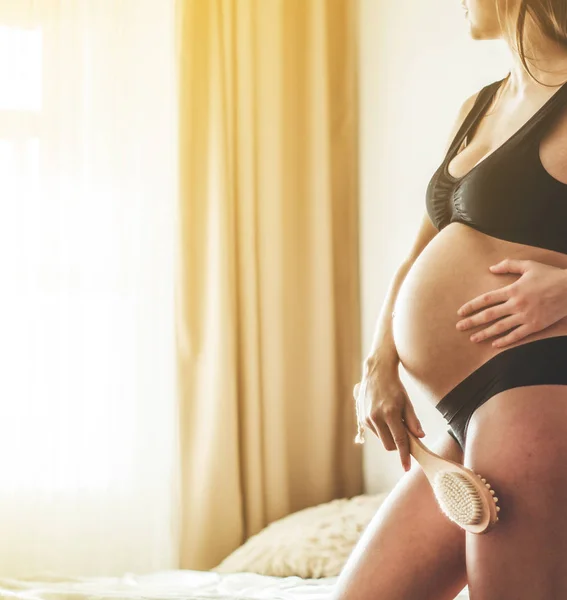 Pregnancy and dry massage. Pregnancy Woman holding dry brush to top of her leg