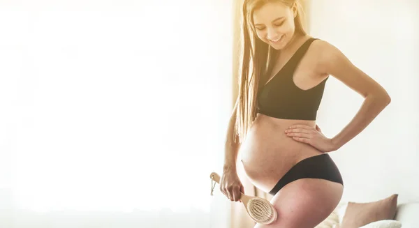 Pregnancy and dry massage. Pregnancy Woman holding dry brush to top of her leg