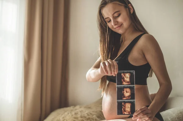 Mulher grávida segurando imagem de ultra-som. Conceito de gravidez, cuidados de saúde, ginecologia, medicina — Fotografia de Stock