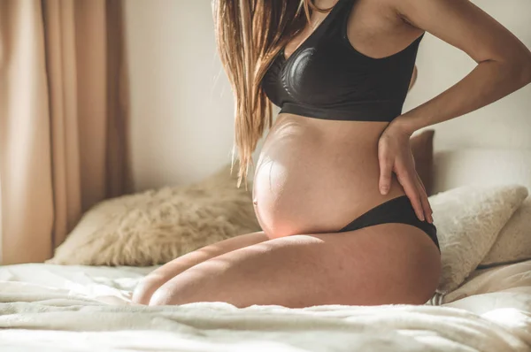 허리 통증 동안 그녀의 아파트에는 침대에 앉아 있는 아름 다운 임신 여성 — 스톡 사진
