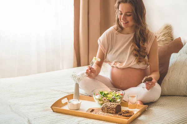 Grossesse et alimentation biologique saine. Femme enceinte dégustant une salade de légumes frais au lit, espace libre — Photo