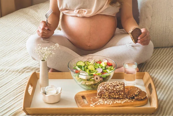 Embarazo y nutrición orgánica saludable. Mujer embarazada disfrutando de ensalada de verduras frescas en la cama, espacio libre — Foto de Stock