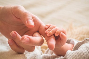 Yeni doğmuş bebeğinin elini tutan kadın eli. Annesi ve çocuğu. Annelik, aile, doğum kavramı