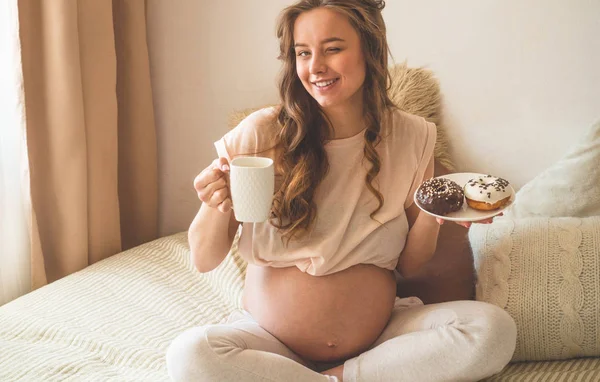 Embarazo y nutrición. Mujer embarazada disfrutando de donas y té en la cama, espacio libre. Concepto de expectativa y salud — Foto de Stock