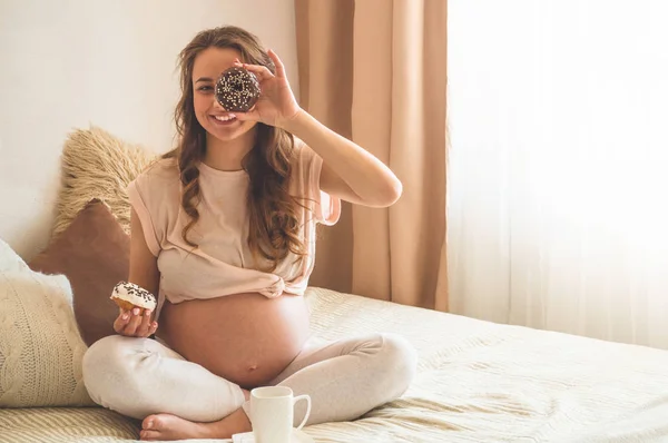Ciąża i odżywianie. Kobieta w ciąży korzystających pączki i herbaty w łóżku, wolne miejsce. Koncepcja oczekiwań i zdrowia — Zdjęcie stockowe
