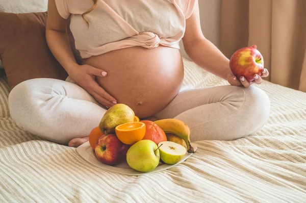 Embarazo y nutrición orgánica saludable. Embarazo y pomelo. Mujer embarazada disfrutando de frutas frescas en la cama, espacio libre . — Foto de Stock