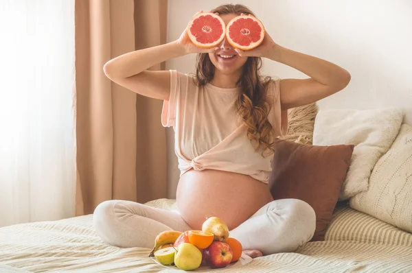 Embarazo y nutrición orgánica saludable. Embarazo y pomelo. Mujer embarazada disfrutando de frutas frescas en la cama, espacio libre . — Foto de Stock