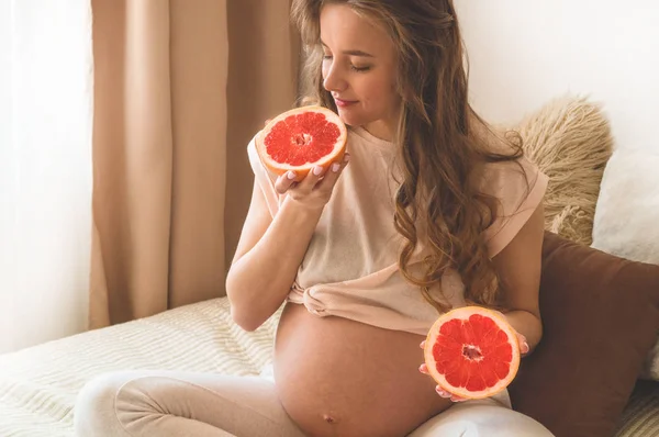 Embarazo y nutrición orgánica saludable. Embarazo y pomelo. Mujer embarazada disfrutando de frutas frescas en la cama, espacio libre . — Foto de Stock