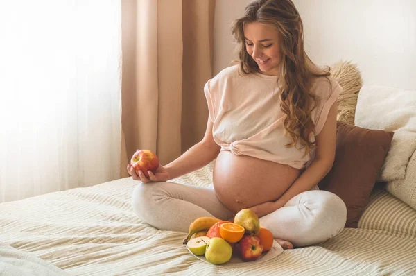 Pregnancy and healthy organic nutrition. Pregnancy and grapefruit. Pregnant woman enjoying fresh fruits in bed, free space. — Stock Photo, Image
