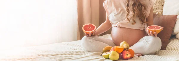 임신과 건강한 유기농 영양. 임신과 자몽. 침대에서 신선한 과일을 즐기는 임산부, 여유 공간. — 스톡 사진