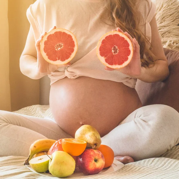 Embarazo y nutrición orgánica saludable. Embarazo y pomelo. Mujer embarazada disfrutando de frutas frescas en la cama, espacio libre . — Foto de Stock