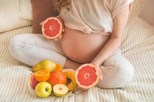 Grossesse et alimentation biologique saine. Grossesse et pamplemousse. Femme enceinte jouissant de fruits frais au lit, espace libre . — Photo