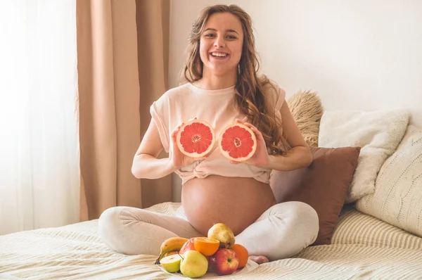 Embarazo y nutrición orgánica saludable. Embarazo y pomelo. Mujer embarazada disfrutando de frutas frescas en la cama, espacio libre . — Foto de Stock