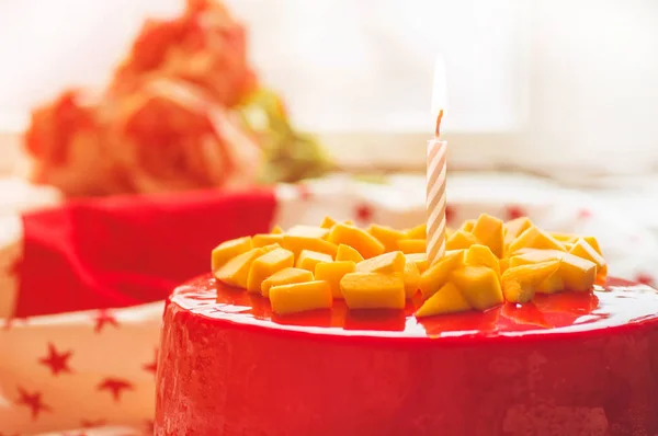 Birthday cake with one candle and red frosting. National bakery. Round cake with mango — Stock Photo, Image