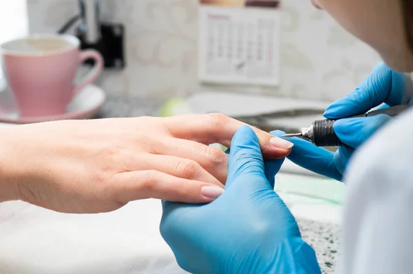 Técnico de uñas dando a un cliente una manicura en el salón de uñas. Joven mujer caucásica recibiendo una manicura — Foto de Stock