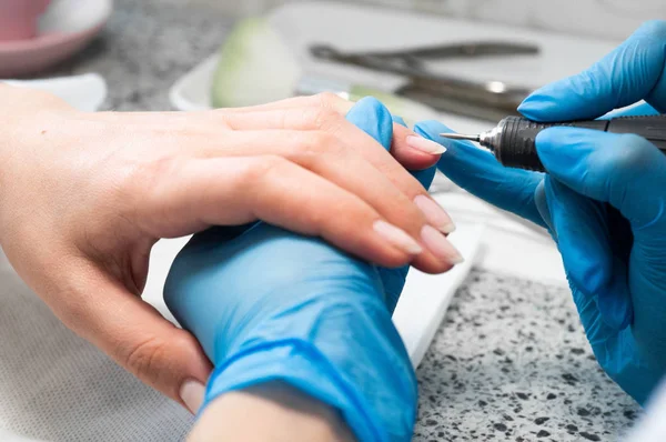 Técnico de uñas dando a un cliente una manicura en el salón de uñas. Joven mujer caucásica recibiendo una manicura — Foto de Stock