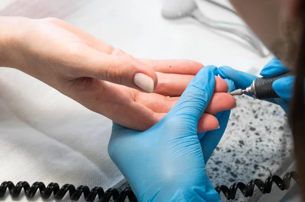 Técnico de uñas dando a un cliente una manicura en el salón de uñas. Joven mujer caucásica recibiendo una manicura — Foto de Stock