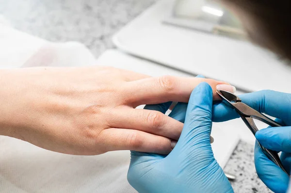 Técnico de uñas dando a un cliente una manicura en el salón de uñas. Joven mujer caucásica recibiendo una manicura — Foto de Stock