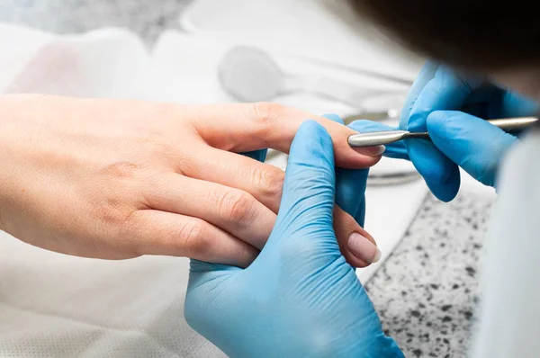 Técnico de uñas dando a un cliente una manicura en el salón de uñas. Joven mujer caucásica recibiendo una manicura — Foto de Stock