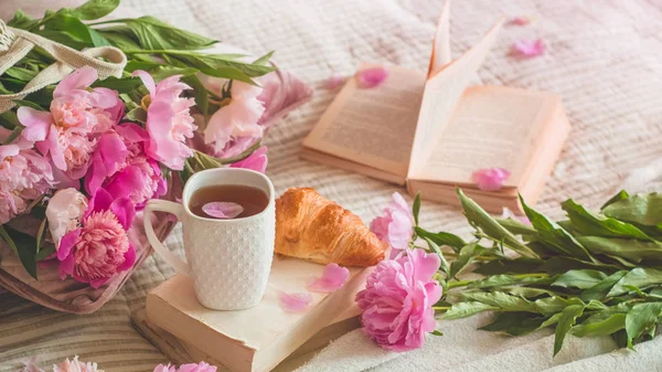Ainda detalhes da vida em casa interior da sala de estar. Xícara de chá com flores Pions e decoração de primavera nos livros . — Fotografia de Stock