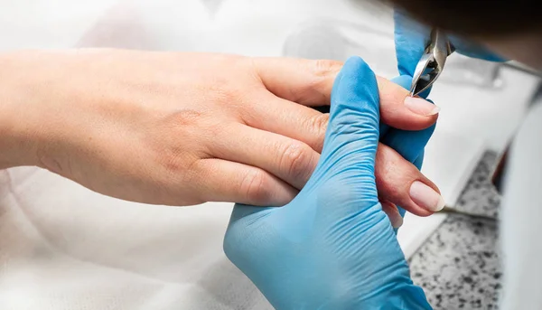 Técnico de uñas dando a un cliente una manicura en el salón de uñas. Joven mujer caucásica recibiendo una manicura — Foto de Stock