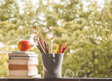 Okula geri dön ve mutlu zaman! Elma, pencerede kitap ve kalem yığını
