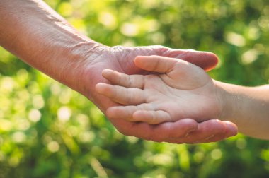 Childs 'ın eli ve yaşlı büyükanne. Çocukları ve yaşlıları koruyan aile kavramı