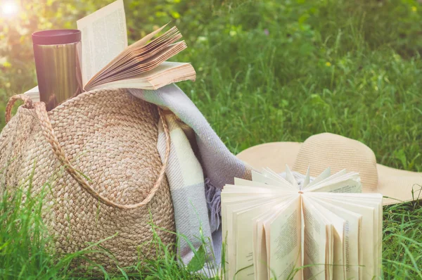 Saco de palha, livro, chapéu e copo térmico em um dia ensolarado de verão — Fotografia de Stock