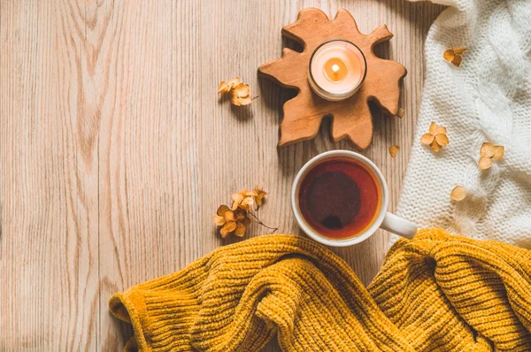 Background with warm sweaters and cup tea. Cozy still life in warm shades, space for text, Autumn winter concept. — Stock Photo, Image