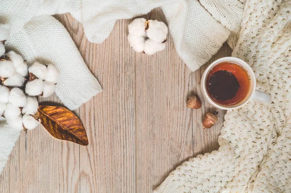 Hintergrund mit warmen Pullovern und Tasse Tee. Kuscheliges Stillleben in warmen Farbtönen, Raum für Text — Stockfoto