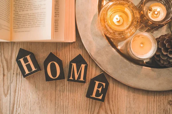 Kitap, kahve fincanı ve ev arka planda birçok mum. Ev ve ev dekorasyonu. Mumlar alev
