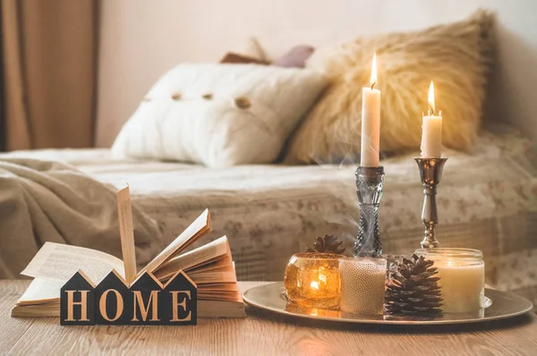 Buku, secangkir kopi dan banyak lilin di latar belakang rumah. Rumah dan rumah dekorasi. Lilin api — Stok Foto