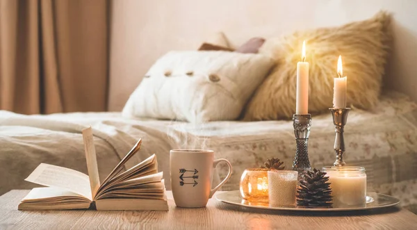 Книга, чашка кофе и много свечей на домашнем фоне. Интерьер дома и дома. Свечное пламя — стоковое фото