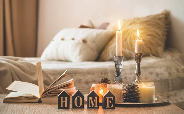 Libro, taza de café y muchas velas en el fondo del hogar. Decoración del hogar y el hogar. Velas llama — Foto de Stock